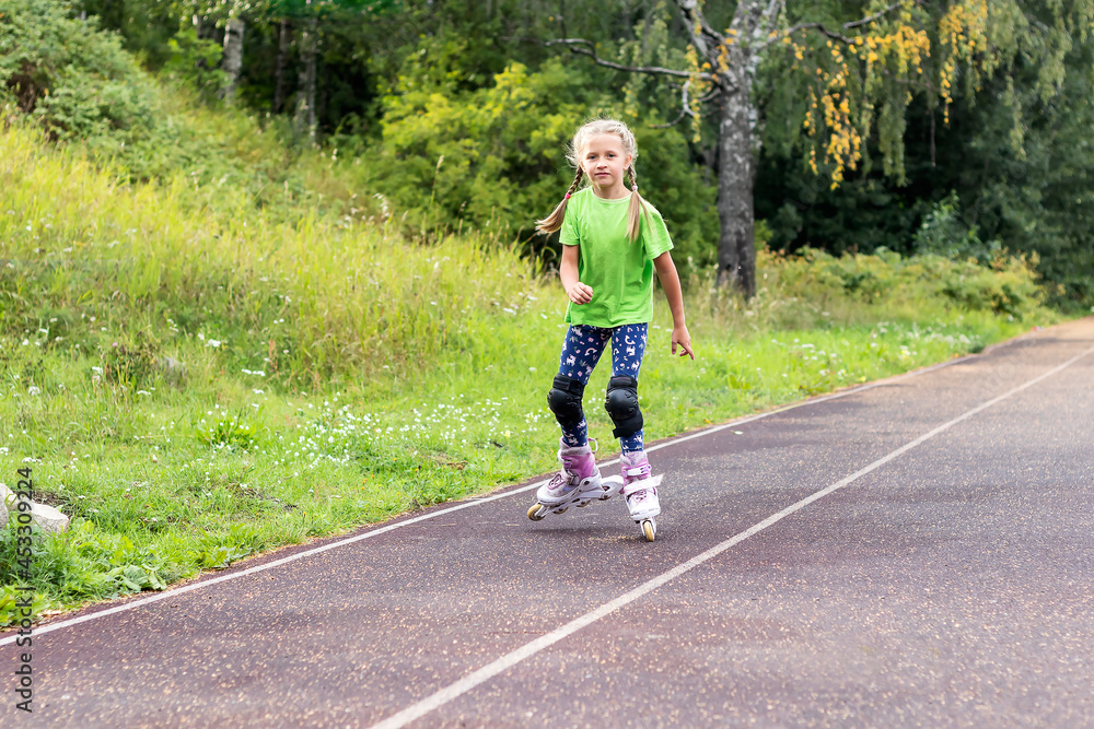 An active girl learns to roller skate on a hard surface at the stadium. An active girl learns to roller skate on a hard surface at the stadium.