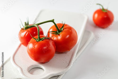 Ripe tomatoes on a branch, ceramic boards for serving, white background © mira_y