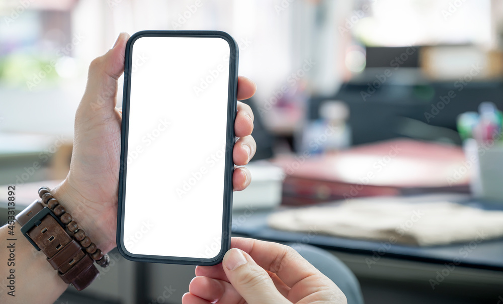 Closup man hland holding blank screen smartphone while sitting at the table in modern office. Closup man hland holding blank screen smartphone while sitting at the table in modern office.