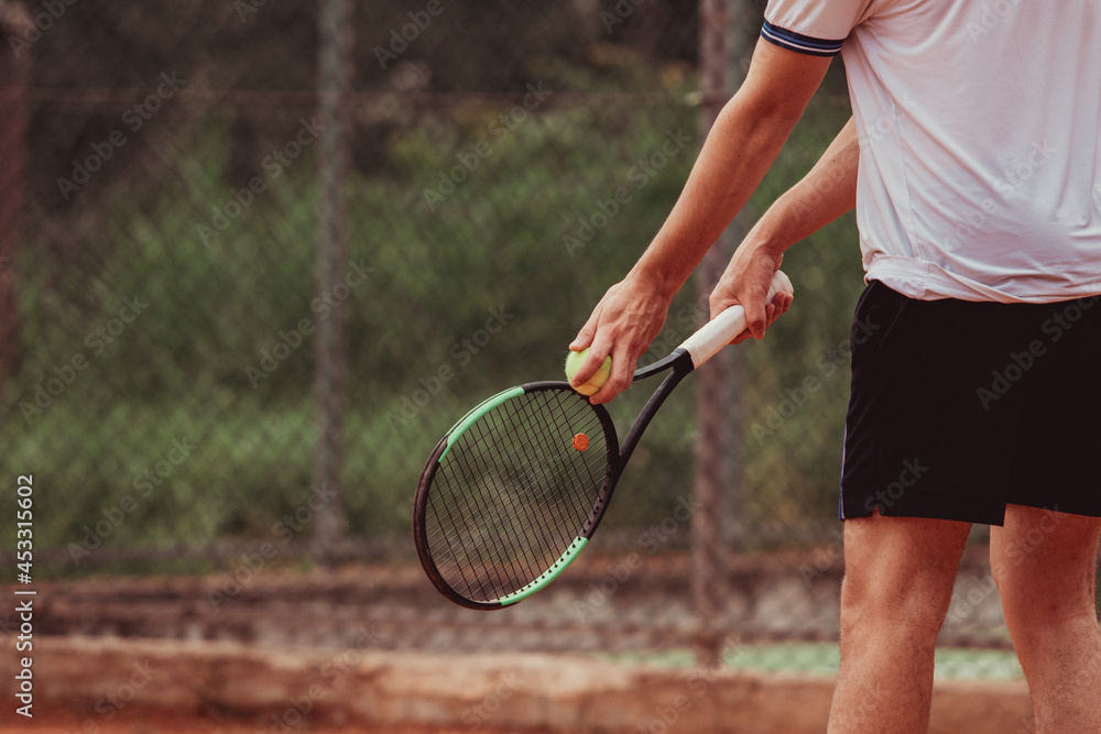 Detail of hands holding a tennis racket and ball during a tennis match. The boy is ready to serve with determination.