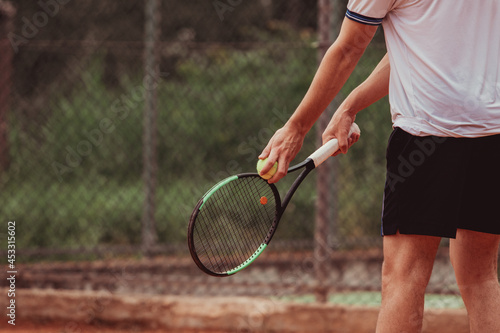 Detail of hands holding a tennis racket and ball during a tennis match. The boy is ready to serve with determination.