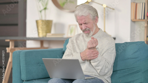 Senior Old Man with Laptop having Wrist Pain at Home