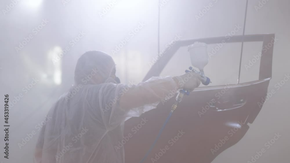 Industrial spray painting process. Auto painter spraying red paint on