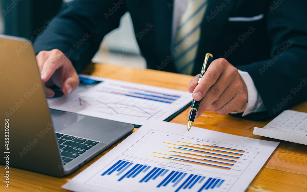 Businessman working on desk with using calculator and computer in the office. concept accounting finance, Businessman working on a graph document financial report and analysis calculation investment Businessman working on desk with using calculator and computer in the office. concept accounting finance, Businessman working on a graph document financial report and analysis calculation investment