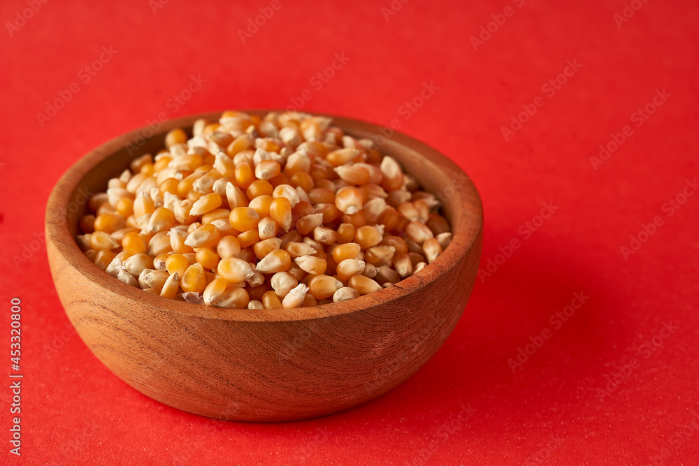 Field Corn in wooden bowl on red background popcorn Field Corn in wooden bowl on red background popcorn