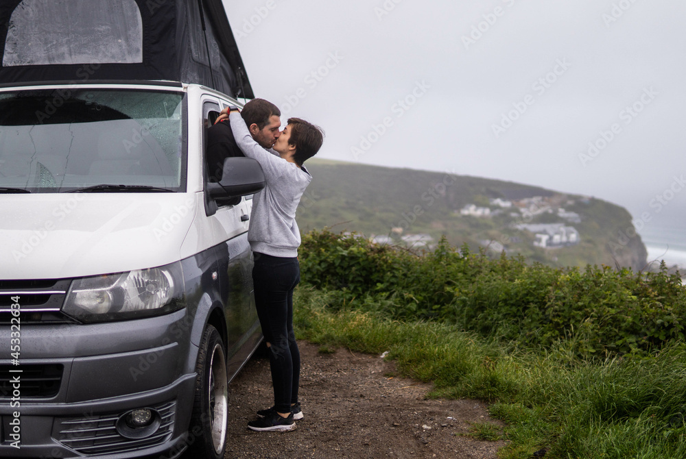 Young couple kissing while travelling in a van around the world. Simple things. Happy romantic couple, nomad travel.