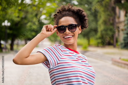 Photo portrait laughing woman wearing glasses striped t-shirt walking in city sunny weather
