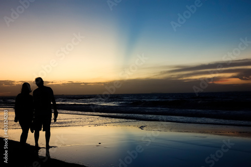 romantic couple silhouette on sunset with colors reflecting in the sky and the sea © Caio