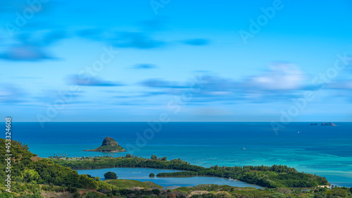 View of Mokoli'i island, Moku Manu and Moli'i Fishpond in O'ahu, Hawaii. Ancient fishing ponds of Hawaii surrounded by crystal clear blue ocean on a sunny day with some clouds in sky