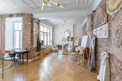 bright workshop room for the creation and work of an architect and artist in a loft style with brick walls and parquet. the walls are decorated with examples of stucco.