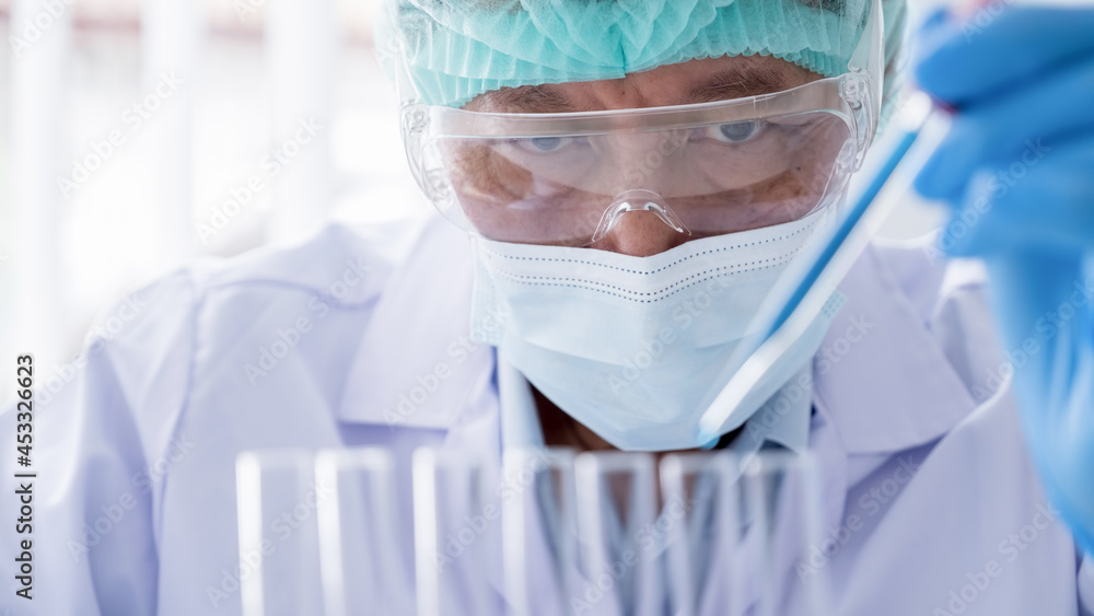 Medical or scientific researcher or man doctor looking at a test tube of clear solution in a laboratory Medical or scientific researcher or man doctor looking at a test tube of clear solution in a laboratory