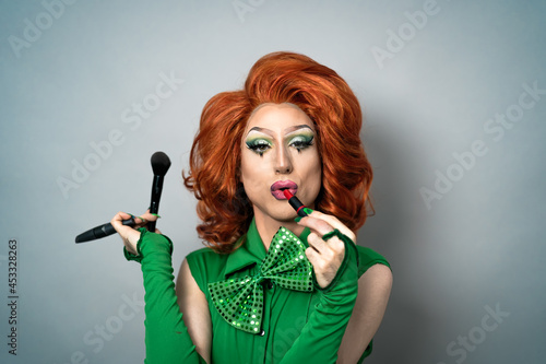 Happy drag queen having fun while doing makeup in studio photo