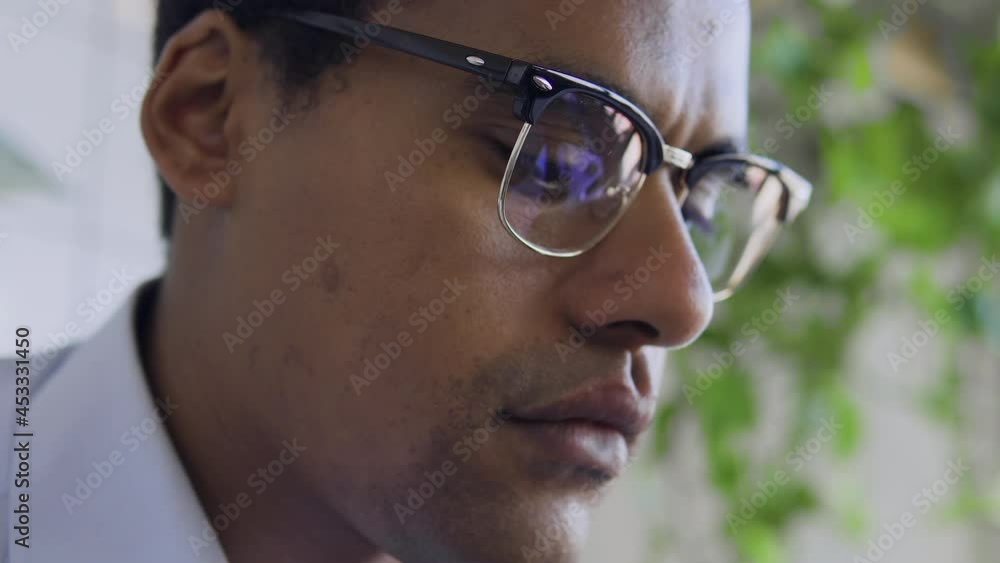 Black man freelancer working on laptop, reflection in eyeglasses, close-up face Black man freelancer working on laptop, reflection in eyeglasses, close-up face
