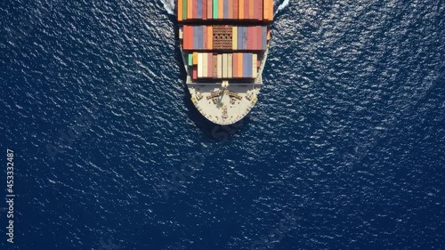 High aerial top down view to a heavy loaded container cargo vessel traveling over blue sea
