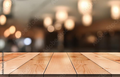 Empty wooden table top with lights bokeh on blur restaurant background. © DEEP PIXEL
