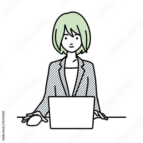 デスクで座ってPCを使っているスーツの女性