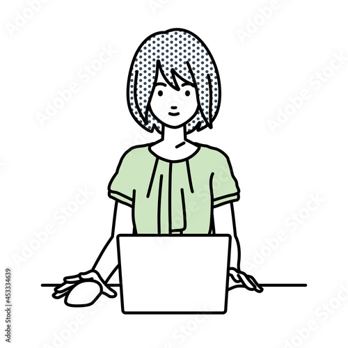 デスクで座ってPCを使っているオフィスカジュアルの女性