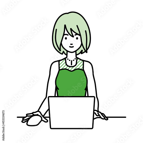 デスクで座ってPCを使っているドレスの女性