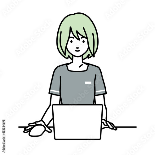 デスクで座ってPCを使っているエステ店員の女性