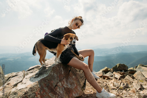 sporty young woman with a dog on top of the mountain