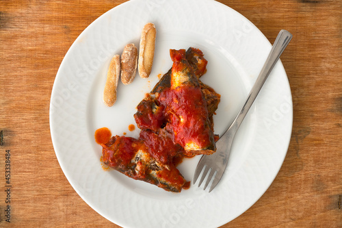 Plate with sardines in tomato. Various sardines with tomato sauce, a fork and bread peaks