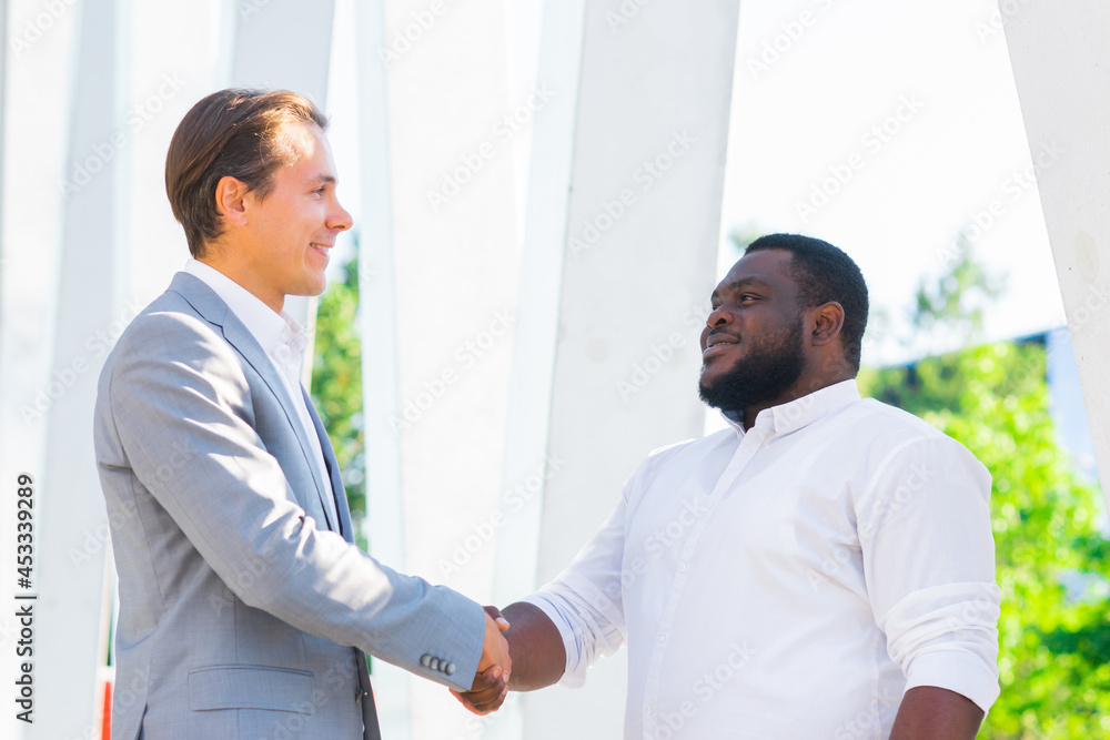 African-American businessman and his colleague in front of modern office building. Financial investors are talking outdoor. Banking and business concept.