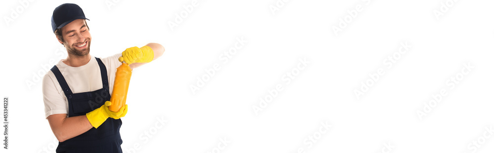 Smiling cleaner in overalls and rubber gloves opening bottle of detergent isolated on white, banner Smiling cleaner in overalls and rubber gloves opening bottle of detergent isolated on white, banner