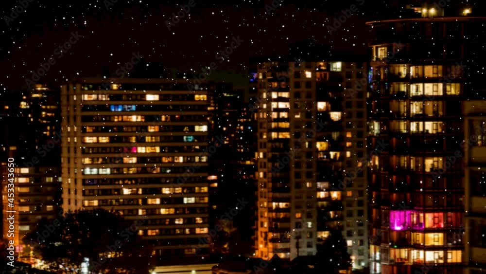 Snow falling against view of tall buildings at night in background Snow falling against view of tall buildings at night in background
