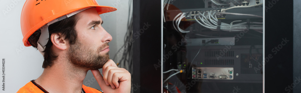 Side view of pensive repairman looking at switchboard, banner Side view of pensive repairman looking at switchboard, banner
