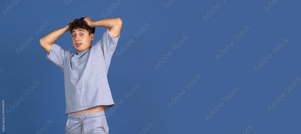 Flyer. Portrait of young curly man isolated over blue studio background with copyspace for ad. Concept of human emotions, fashion, beauty, youth Flyer. Portrait of young curly man isolated over blue studio background with copyspace for ad. Concept of human emotions, fashion, beauty, youth