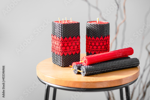 Black and red handmade wax candles with red lace ribbon On backless chair. Interior decor. photo