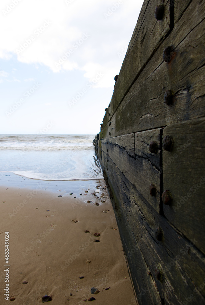 The tide coming in along a wooden groyne on the beach at Frinton-on-Sea, Essex, UK
