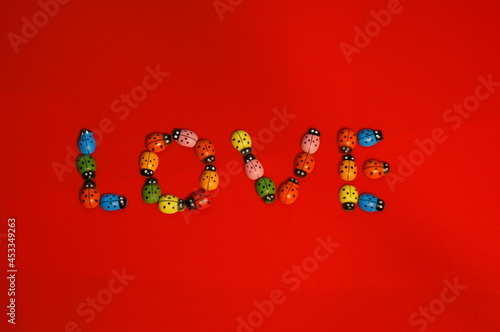 The word love consists of figures of ladybugs on a red background.