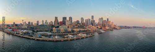 Aerial panoramic view of Seattle, Washington. Skyscrapers can be seen with a sunset along with an ocean bay with boats. 
