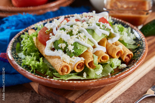 Flautas de pollo con lechuga, tomate, crema y queso photo