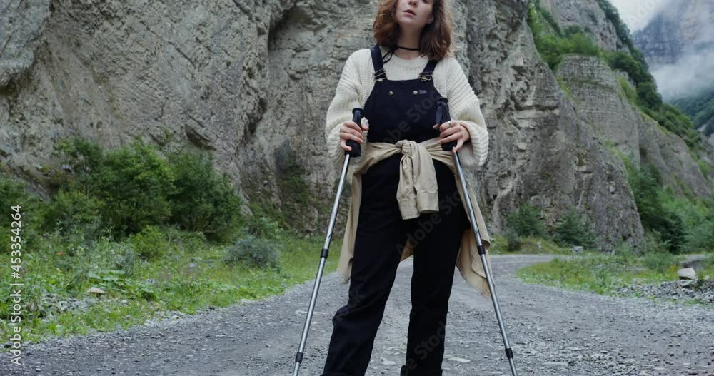 Elbrus. Young woman stands on mountain road with sticks for sports walking Elbrus. Young woman stands on mountain road with sticks for sports walking