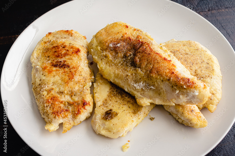 Browned Breaded Chicken Cutlets on a White Plate: Thinly cut chicken breasts that have been pan-fried on a plate