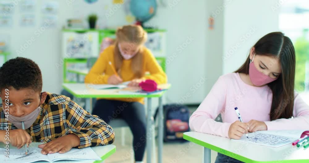 Close up of multi-ethnic diverse school children sitting in classroom writing in copybook with pencil, studying, education learning concept Male and female junior students sitting at desk in classroom Close up of multi-ethnic diverse school children sitting in classroom writing in copybook with pencil, studying, education learning concept Male and female junior students sitting at desk in classroom