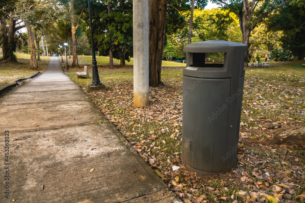 Trash can in a natural park on the side of the road, surrounded by trees. Trash can in a natural park on the side of the road, surrounded by trees.