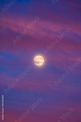 Perigee Moon (Supermoon) surrounded by purple clouds at sunset with a dark blue sky, closest point of our satellite to planet Earth