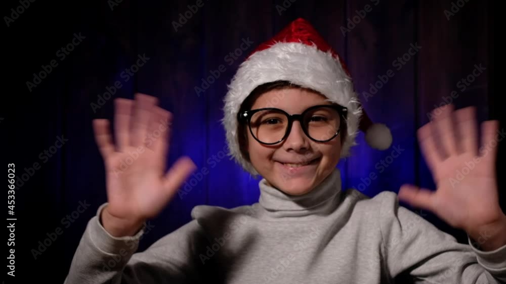 Child in a red hat and glasses looking at webcam. Little boy calls his family over internet. Christmas in quarantine. Child in a red hat and glasses looking at webcam. Little boy calls his family over internet. Christmas in quarantine.