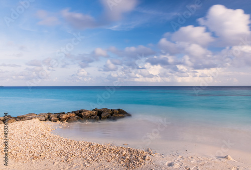 Long exposure water of Indian ocean with stones on the Maldivian island. Sunset time. Crossroads Maldives  july 2021