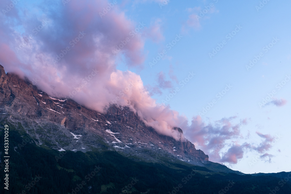 des nuages roses couvrent les sommets d'un massif montagneux