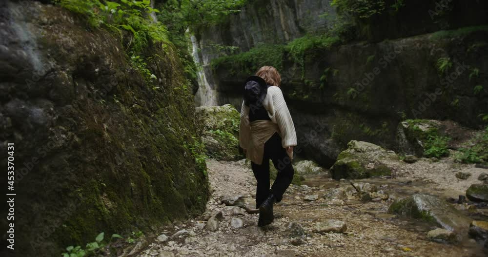 Russia, Caucasus. A young woman crosses a seething mountain stream on stones Russia, Caucasus. A young woman crosses a seething mountain stream on stones