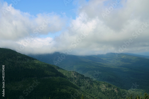 Karkonosze in the summer. View of the mountains covered with green trees. Thick clouds over the mountains. Karkonosze National Park 