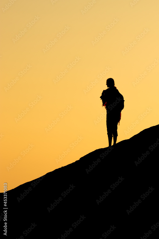 Silhouette of a girl over the hill at sunrise