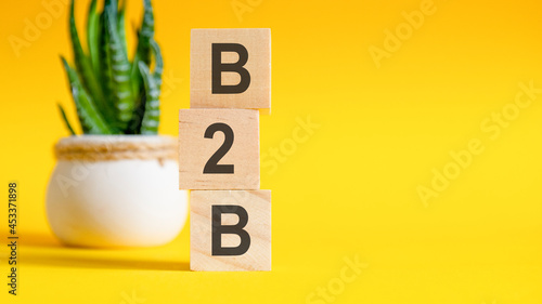 b2b concept with wooden blocks on table, yellow background