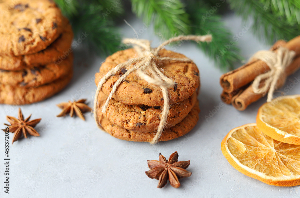 Ginger Christmas cookies with chocolate chips on a gray background among the Christmas tree branches. Christmas pastries. Ginger Christmas cookies with chocolate chips on a gray background among the Christmas tree branches. Christmas pastries.