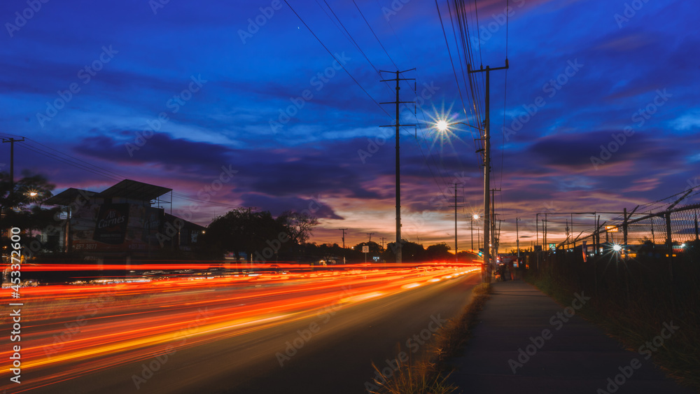 Paisaje urbano con el trafico en forma de haces de luces de fondo, tomada con larga exposición con destaques en azul, rojo y naranja 