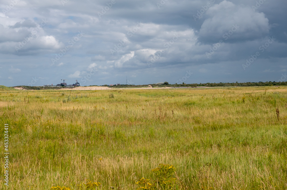 Knokke-Heist, Flanders, Belgium - August 6, 2021: Zwin Nature Reserve. Approaching rain storm cloudscape over green landscape. Cadzand construction site on horizon.